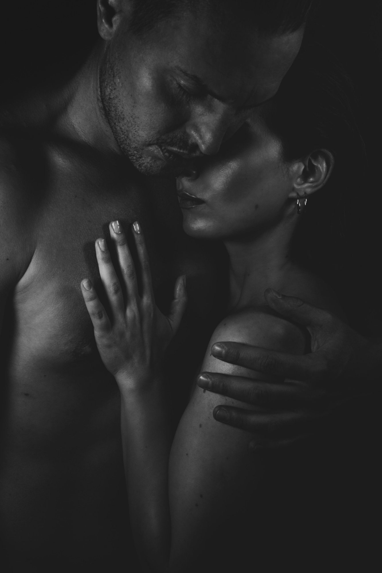 A couple in a close, tender embrace, her hand resting on his chest