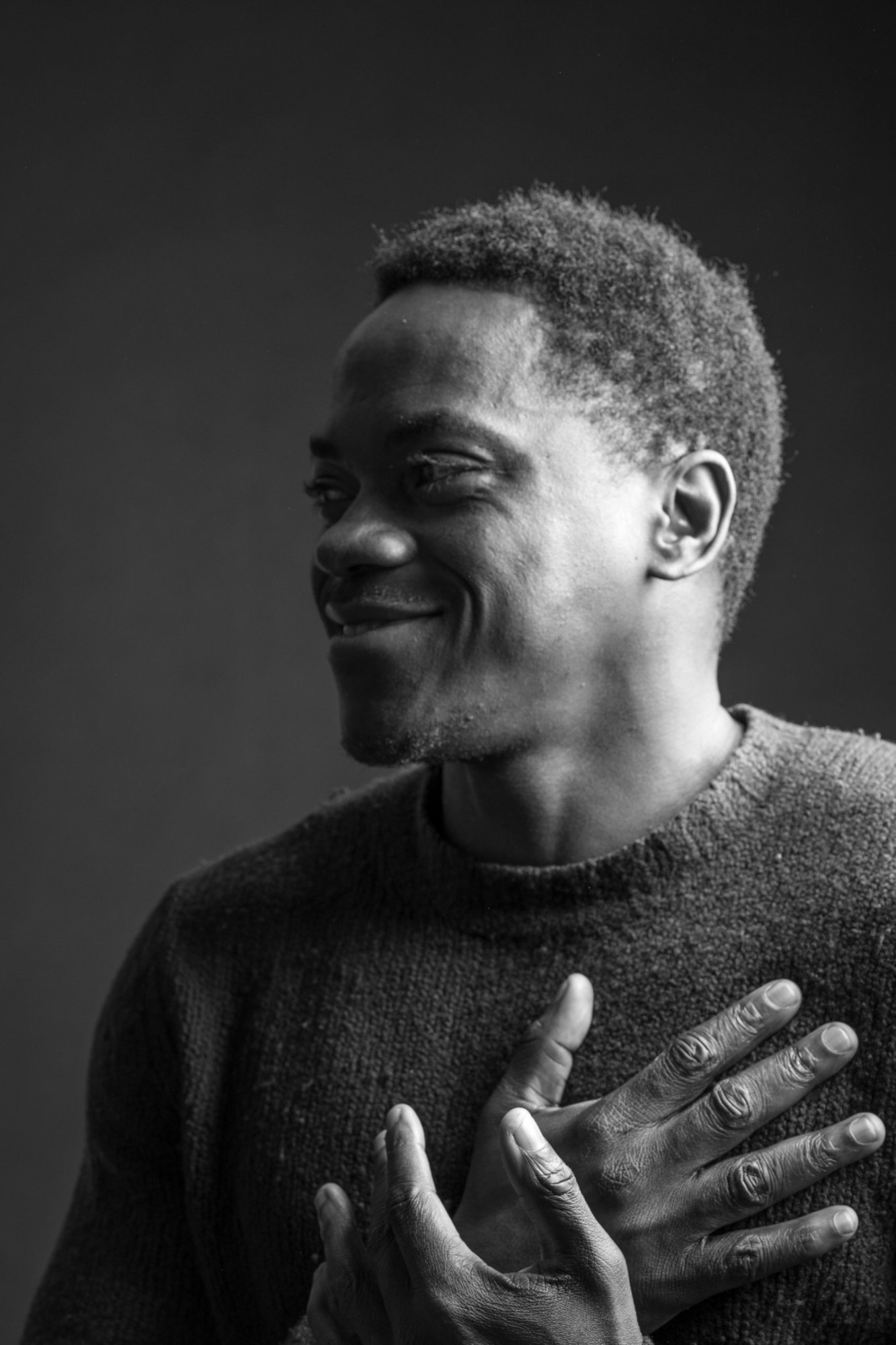 A smiling man with both hands resting on his heart