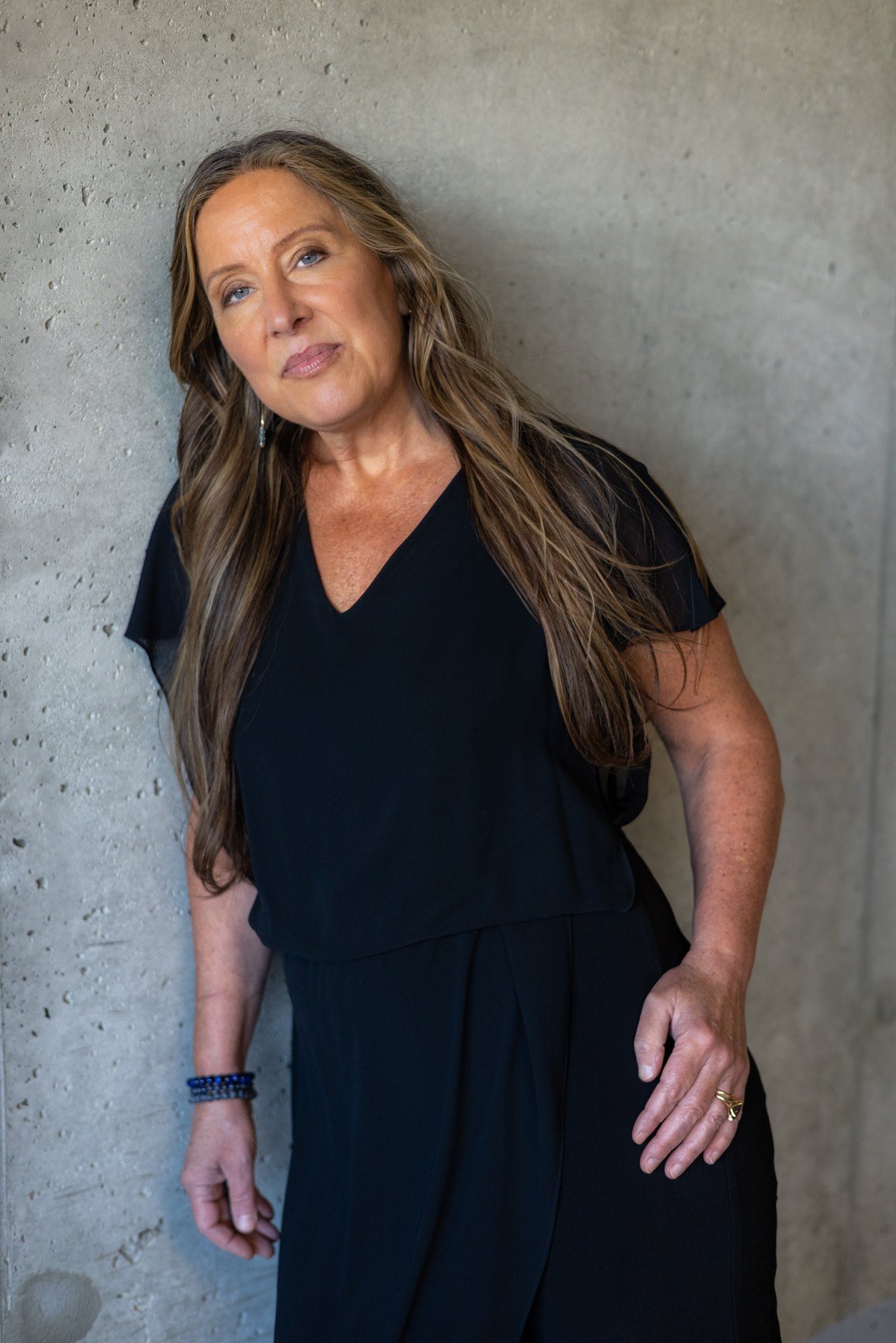 Lisa Watson in a black dress leaning against a concrete wall